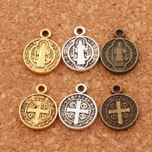 Saint Benedict Medal pendants in gold, silver, and bronze with antique finish on wood