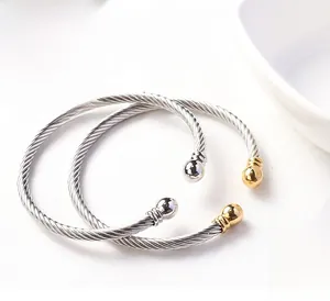 Detail of twisted cable bangles in stainless steel with silver and 18k gold tone spheres