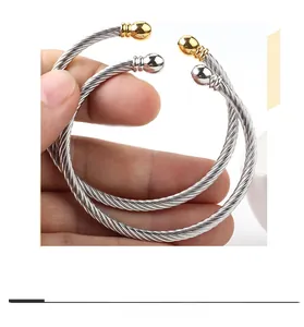 Detailed view of twisted cable C-shape bangles in silver and gold with ball end caps
