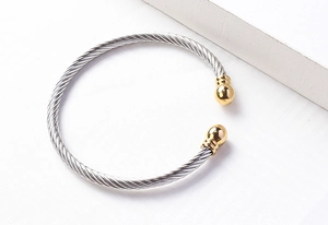 Detail of twisted cable cuff bracelet in silver with gold spherical end caps