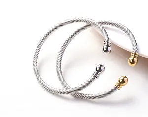 Detailed close-up of twisted cable steel bracelets in silver and 18k gold duo-tone finish