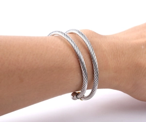 Detail of silver twisted cable cuff bracelet with spherical ends on model's wrist
