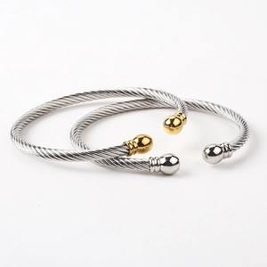 Close-up of twisted steel cable bracelets with gold end caps and silver finish