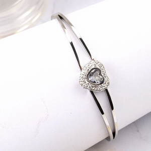 Bracelet cœur argenté orné de cristaux de zircone blancs sur un support de présentation