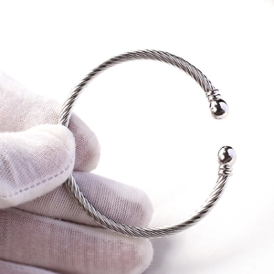 Detail of twisted cable silver bangle with polished metal end beads held in a white glove