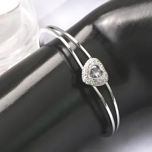 Détail du bracelet ouvert argenté à double rangée avec un charm coeur étincelant en diamant