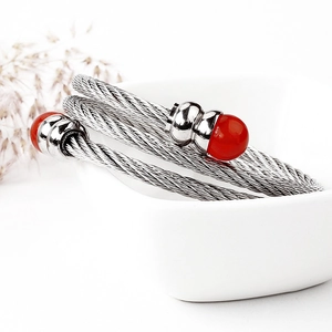 Bracciale rigido a cavo ritorto argento con perline rosse su ceramica minimalista