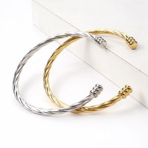 Twisted titanium steel open cuff bracelets in gold and silver plating on stone stand