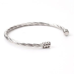 Close-up of silver twisted wire open bangle with cylindrical end caps and industrial design