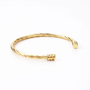 Macro detail of the twisted rope design on an 18k gold-plated stainless steel cuff bracelet