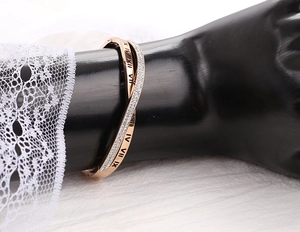 Gros plan sur un bracelet croisé or rose avec chiffres romains et cristaux brillants