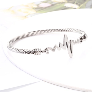 Macro detail of silver twisted cable bracelet with ECG heartbeat center element
