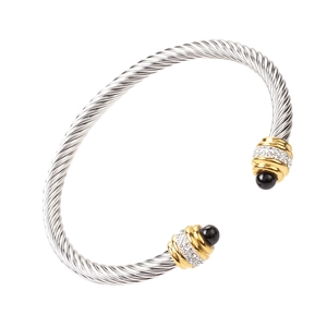 Macro detail of twisted steel bangle featuring sparkling crystals and black bead accents