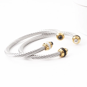 Detailed view of twisted steel cable bangles with gold hardware and inlaid crystals