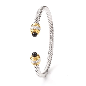Macro detail of two-tone cable twist bangle with pave rhinestones and black beads