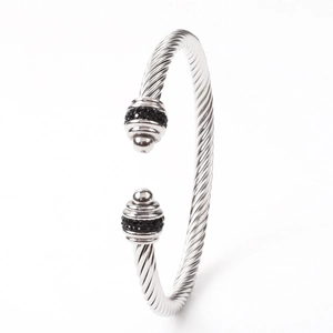 Detailed close-up of twisted silver cable bangle featuring black crystal-encrusted end caps