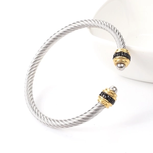 Detail of twisted steel wire bracelet with gold-plated rings and black stone inlay