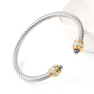 Macro detail of silver cable bangle with gold crystal accents and dark spherical ends