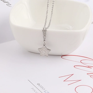 Collier élégant avec pendentif étoile en acier inoxydable sur décor d'assiette blanche