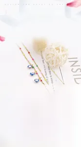 Detail of gold evil eye anklet with colorful beads and charms on a stylish background