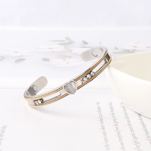Detail of C-shaped magnetic therapy bangle with opal heart and gold braided edges