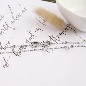 Détail de la chevillère double couche argentée avec perles blanches et symbole infini