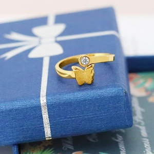 Détail d'une bague papillon dorée avec cristal posée sur un coffret cadeau bleu