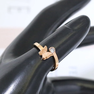 Détail macro d'une bague papillon en or rose avec ailes mates et diamant rond étincelant