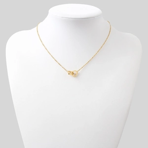 Détail d'un collier doré élégant avec pendentifs cœur et cercle entrelacés sur un buste