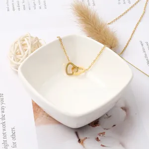 Détail du pendentif double cœur doré entrelacé sur une chaîne de collier délicate