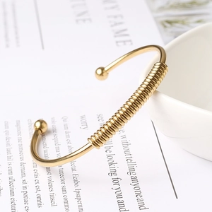 Detailed close-up of a gold spring bangle with spiral texture resting on a ceramic bowl