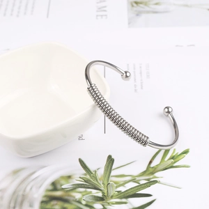 Detail showing silver stainless steel spring bracelet with spiral texture and ball ends