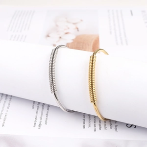 Detail of gold and silver minimalist spring bracelets with textured metal coils