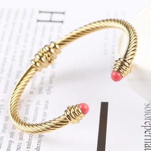 Macro view of 18K gold twisted cable cuff bracelet with pink cabochon ends and detail ring