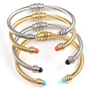 Detail of twisted cable cuff bracelets in gold and silver with colorful end caps
