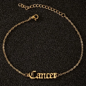 Nahaufnahme der goldenen Krebs-Sternzeichen-Fußkette mit gotischer Schrift auf Leder