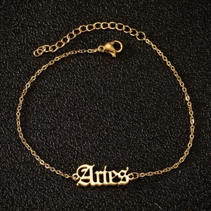 Detail der goldenen Widder-Fußkette mit gotischer Schrift und verstellbarem Verschluss