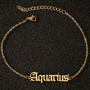 Makroaufnahme der goldenen Wassermann-Fußkette mit gotischer Schrift auf schwarzem Leder