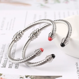 Macro detail of twisted silver steel bracelets with decorative red and black bead ends