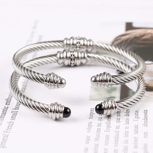 Close-up of twisted cable cuff bracelets in silver finish with black bead detailing