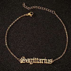 Detail der goldene Schütze Anhänger mit gotischer Schrift an einer Fußkette