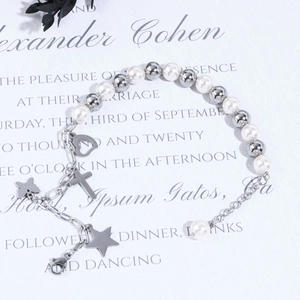 Detail view of pearl and silver bead bracelet with heart, cross, and butterfly charms