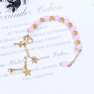 Detail of pink crystal beads and golden charms with heart and cross on the chain
