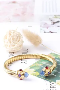Dettaglio macro del bracciale a cavo in titanio dorato con pietre occhio di gatto azzurre