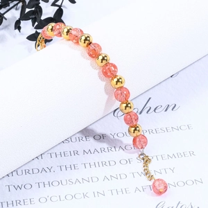 Macro detail of beaded bracelet with gold accents and pink strawberry quartz stones