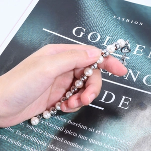 Detail of beaded bracelet with white pearls, silver metal spheres and a heart charm