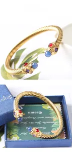 Dettaglio del bracciale rigido a cavo dorato con pietre preziose miste e scatola regalo