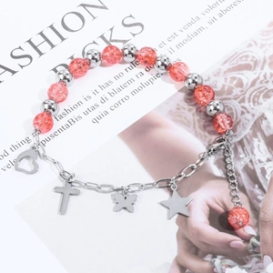Detail of beaded bracelet with orange glass beads, silver cross and heart charms