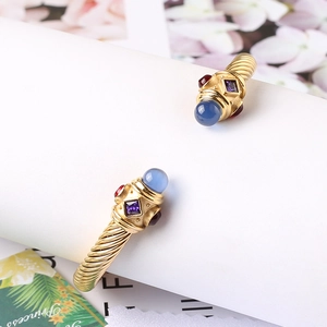 Dettaglio macro del bracciale a torsione dorato con cabochon blu e pietre preziose viola