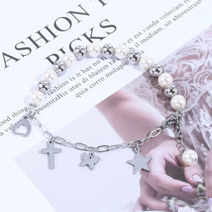 Detail view of pearl chain bracelet with silver heart, cross, and butterfly charms